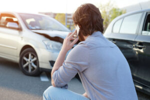 man calling help after a car crash accident on the road